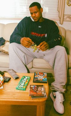 a man sitting on top of a couch next to a table with books and snacks