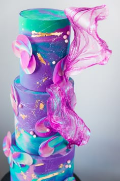 a multi - colored cake with pink, blue and green icing on it's top