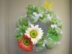 a green mesh wreath with white daisies and butterflies on the front door for spring