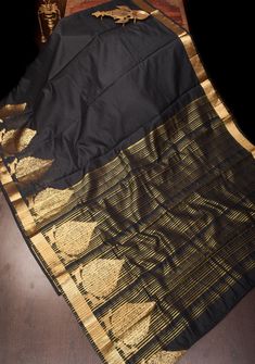 This sophisticated black art silk saree is a stunning example of classic elegance with a contemporary twist. The saree features intricate damask buttas that add a touch of timeless charm, while the zari border enhances its luxurious appeal with a subtle golden shimmer. Perfect for formal events and evening gatherings, this saree offers a refined and versatile look. Please note that it does not come with a blouse piece, allowing for personalized styling to match your unique taste This saree is ready to wear with fall and pico done.  *Note: There may be minor variations in the shade, the texture of the product. Hues/textures show differently due to variations in screen settings and other factors, *Note: This is a handmade saree and there may be slight inconsistencies such as in it's embroide Luxury Black Art Silk Blouse Piece, Luxury Black Art Silk Sets, Luxury Black Raw Silk Saree, Luxury Black Tissue Silk Saree, Luxury Fall Evening Suits, Luxury Black Saree With Woven Motifs, Luxury Art Silk Saree With Embroidered Border, Luxury Black Paithani Silk Saree, Art Noir