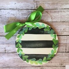 a wooden ornament decorated with green leaves and ribbon on top of a table