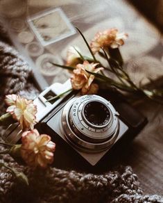 a camera sitting on top of a bed next to flowers