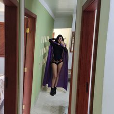 a woman in a black bodysuit and purple cape taking a selfie