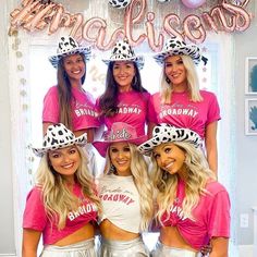 a group of women wearing matching pink shirts and hats