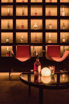 a glass table with bottles on it in front of a wall full of liquor bottles