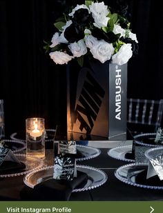 a vase with white flowers on top of a table next to candles and napkins