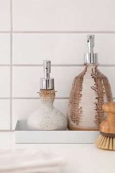 two soap dispensers sitting on top of a counter