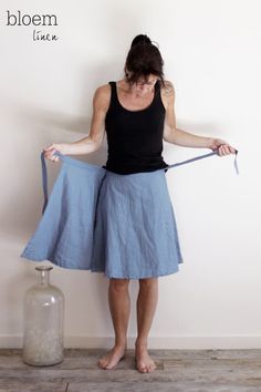 a woman is holding a blue skirt while standing in front of a white wall