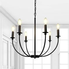 a black chandelier with five lights hanging from it's sides in a white room