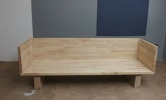 a wooden bench sitting on top of a hard wood floor next to a blue wall