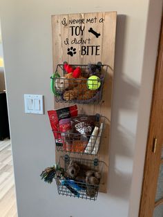 a wall mounted basket filled with food next to a wooden sign that says i never met a toy but it didn't bite