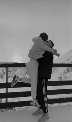 a man and woman hugging on top of a snow covered mountain