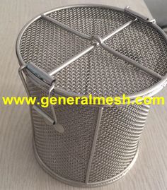 a metal mesh basket on a table with the lid open and two handles attached to it