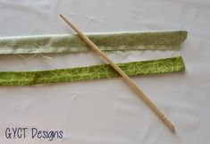 two pieces of green fabric with wooden knitting needles