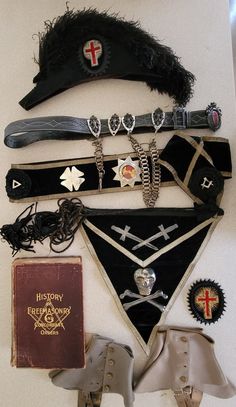 Offered is an Antique Masonic Knights Templar Uniform Lot, just acquired from an estate.  It consists of a hat, sash with medallions and pins, belt with commemorative plates and chains and a large buckle, an apron with a sterling skull and crossbones, and crossed sterling swords, and a book from 1895, History of Freemasonry and Concordant Orders, and 2 pairs of spats. Condition: Hat, a little stiff to open and if handled roughly small feathers will break off. Sash- good condition but shows age.  Rosette ribbons a little wrinkled from storage.  I was told medals were sterling but I did not take them off.  They seem too stiff to me to be sterling.  Light tarnish spots.  One with cross and snake says IN HOC SIGNO VINCES Belt - leather with typical wear, not stiff or torn.  4 sliding medallion Belt Chains, Bone Books, Skull Bones, Belt Leather, Skull And Crossbones, Skull And Bones, Cowboy Hats, 19th Century, Apron