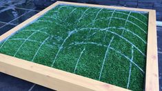 a wooden box with artificial grass in the shape of an american football field on it