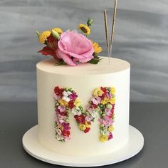 a white cake decorated with flowers and the letter m