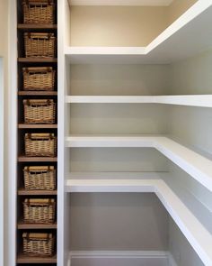 an empty walk in closet with white shelves and wicker baskets on the bottom shelf