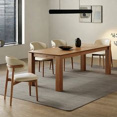 a dining room table with chairs and a vase on the rug in front of it