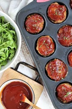 a muffin tin filled with meat and sauce next to a bowl of lettuce