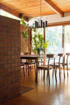 a dining room table with chairs and a brick wall in front of the window,