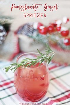 a pink drink with rosemary garnish in a glass on a plaid tablecloth