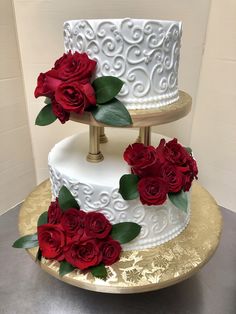 two tiered wedding cake with red roses on the top and gold trimmings