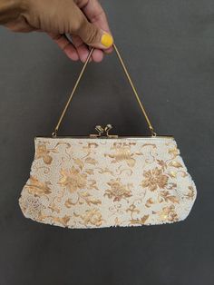 "This is such a unique bag! Made by hand in the 40s in Japan for Schildkraut Bros. It is a beautiful gold floral brocade with white small beads to accentuate and enhance floral details throughout. Gold chain handle with gold closure and rhinestones at top of gold closure snaps gives it that special something every time it's opened. Gold silk interior lining has some black ink stains throughout but the exterior is in perfect condition.  Measurements Length 10\" height 5\" depth 1 1/2\"" Gold Embroidered Handheld Evening Bag, Vintage Party Clutch With Pearl Handle, Vintage Gold Embroidered Evening Bag, Gold Vintage Embroidered Evening Bag, Vintage Gold Handheld Clutch, Vintage Formal Clutch With Pearl Handle, Formal Vintage Evening Bag With Pearl Handle, Gold Clutch With Pearl Embroidery For Evening, Gold Embroidered Evening Bag For Events