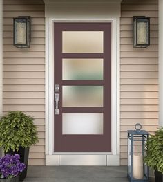 the front door to a house with two plants and a lantern on the side walk