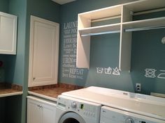 a washer and dryer in a laundry room with chalk writing on the wall