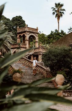 a man standing on some steps in front of a building with palm trees behind him