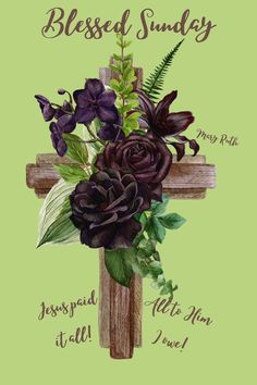 a cross with purple flowers and greenery on it