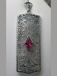 Ruby Pendant Necklace, Rectangle Art Deco style pendant with fine lace filigree and a diamond shaped red ruby gemstone in the center of the filigree, Silver Embrace Jewelry Art Deco Filigree Pendant Jewelry, Art Deco Pendant Jewelry For Anniversary, Art Deco Sterling Silver Filigree Jewelry, Art Deco Filigree Jewelry As Gift, Art Deco Filigree Jewelry For Gift, Art Deco Silver Filigree Jewelry, Art Deco Diamond Cut Pendant, Vintage Silver Diamond Cut Necklace, Vintage Diamond Cut Silver Necklace