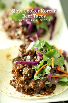 two tacos filled with meat and veggies on top of a white plate