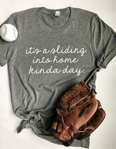 a t - shirt that says it's holding into home kinda day next to a baseball and glove