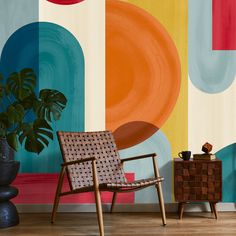 a chair sitting next to a potted plant in front of a colorful wall mural