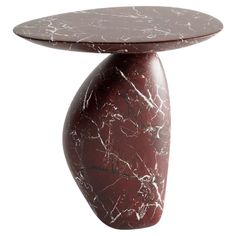 a red marble table with an oval shaped base on the top and bottom, against a white background