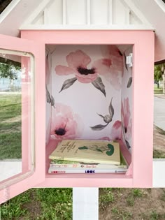 a pink and white box with flowers painted on the side, sitting in front of a window