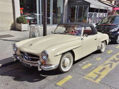 an old car is parked on the side of the street