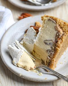 a piece of cake on a white plate with a fork next to it and some pecans in the background