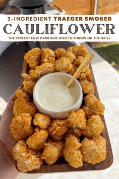 a person holding a plate of fried cauliflower with ranch dip on the side