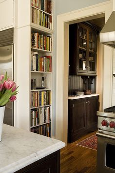 a vase with flowers in it sitting on a kitchen counter next to a stove top oven