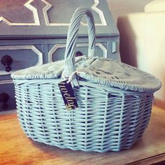 a wicker basket sitting on top of a wooden table next to a white dresser