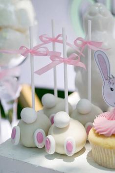 cupcakes with pink frosting and bunny ears on them are sitting on a table