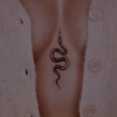 a snake tattoo on the back of a woman's left side ribcage