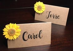 two small cards with yellow flowers on them sitting on a table next to each other