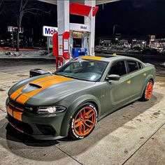 a green and orange car parked in front of a gas station