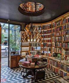 a room filled with lots of books on top of a checkered floor next to a window