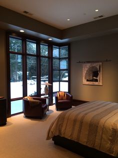 a large bed sitting in a bedroom next to two chairs