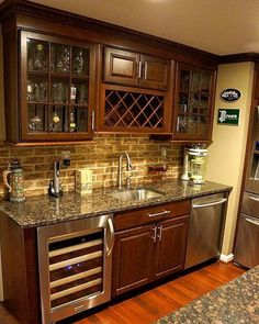 a kitchen with wooden cabinets and granite counter tops, stainless steel appliances and wine glasses